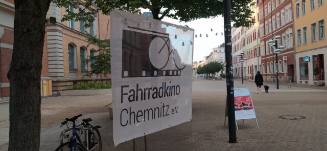 Ein Transparent in einem Baum auf dem Brühl. Zu lesen ist: Fahrradkino Chemnitz e.V.